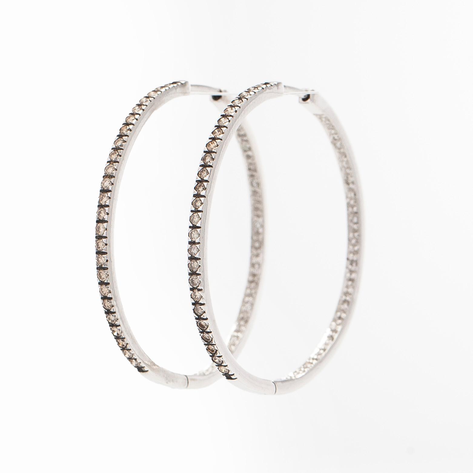 A pair of 14K white gold  hoop earrings with diamonds.