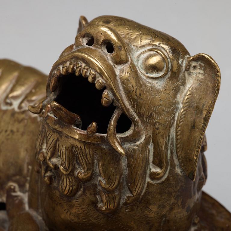 A copper alloy figure of a reclining buddhist lion, presumably 18th Century.