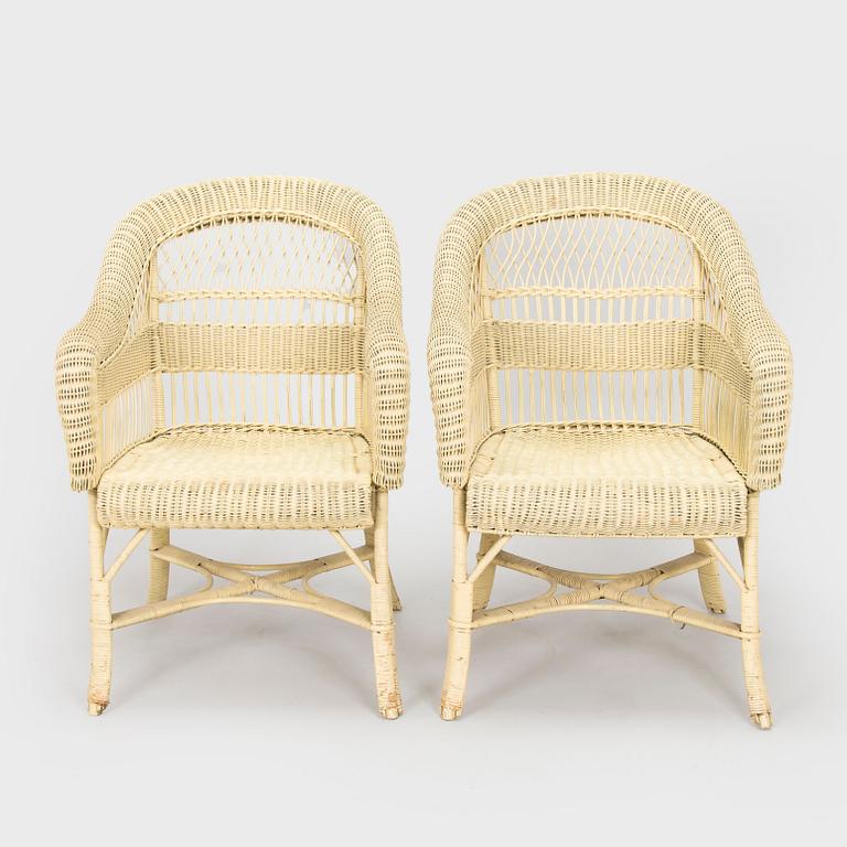 A mid-20th-century three-piece rattan furniture set including two armchairs, and a table.