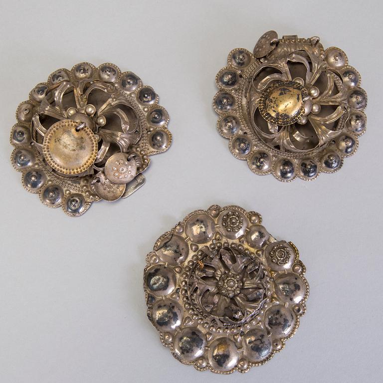A collection of mostly silver, tradition folk buttons and belt buckles.