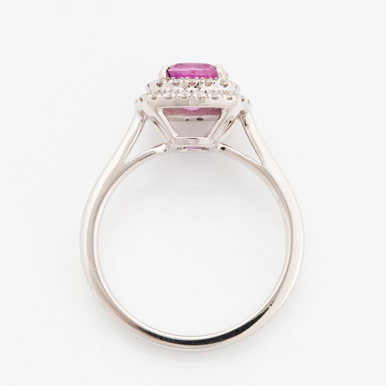 An 18K white gold ring set with a pink sapphire and round brilliant-cut diamonds.