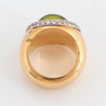 An 18K gold Steinlin ring set with a cabochon-cut peridot and round brilliant-cut diamonds.