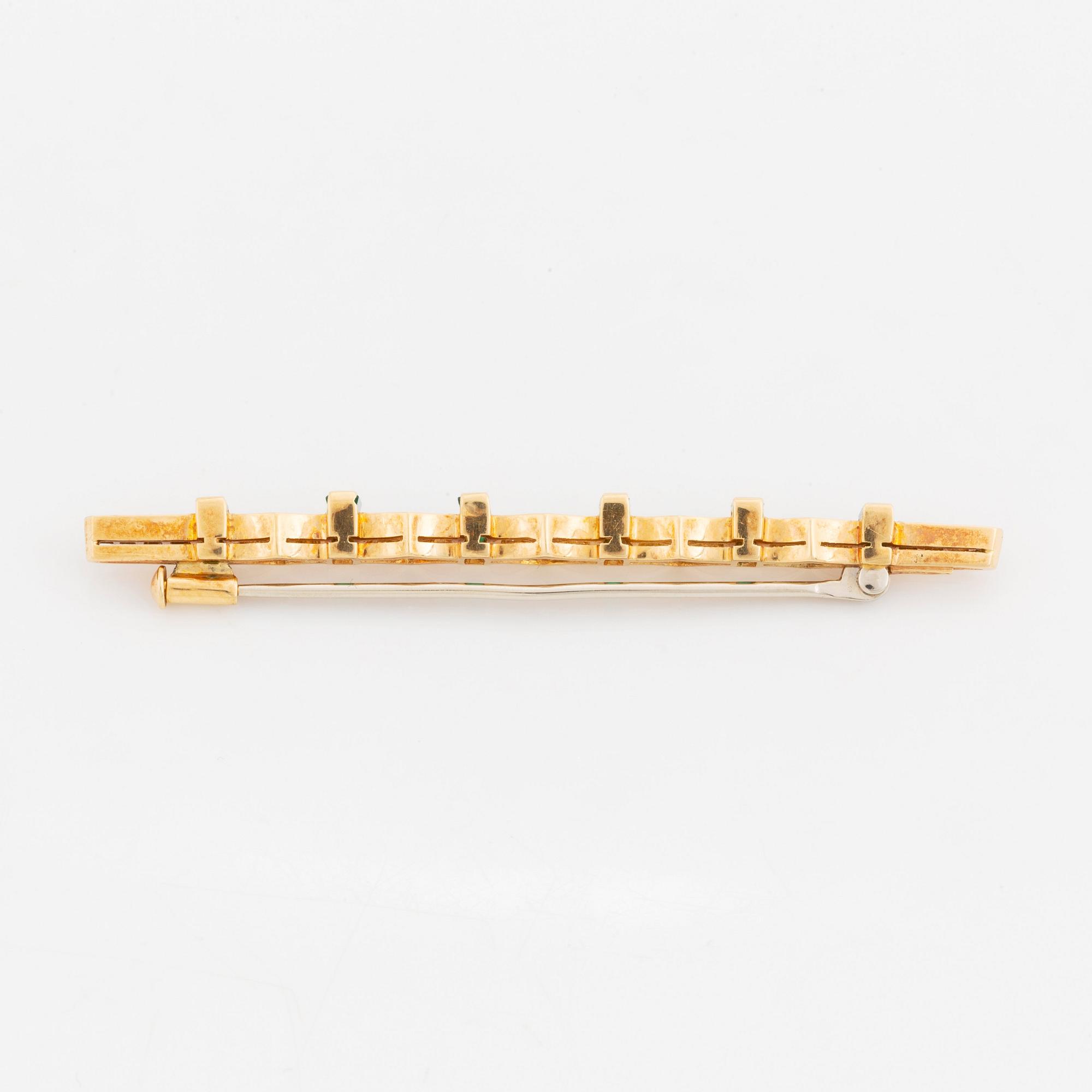 An 18K gold brooch set with step-cut emeralds and round brilliant-cut diamonds.
