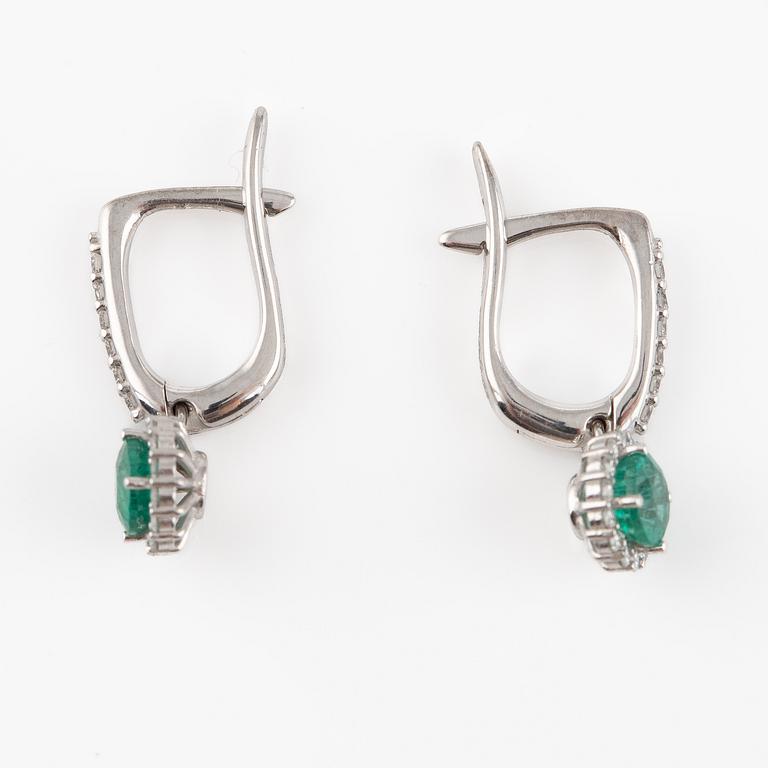 A pair of earrings with faceted emeralds and round brilliant-cut diamonds.