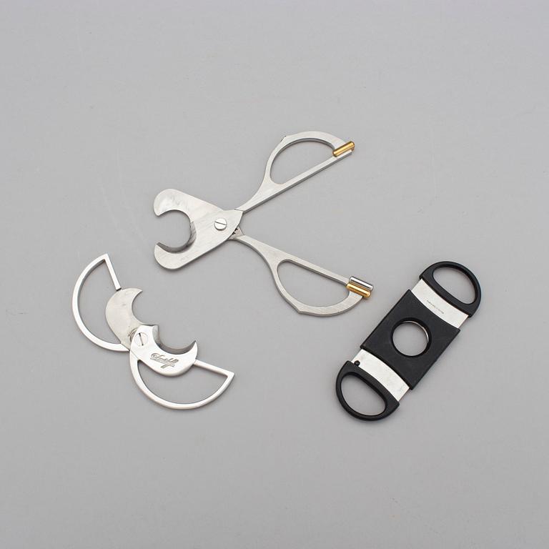 Two cigar cutters from Davidoff and must de Cartier in original cases.