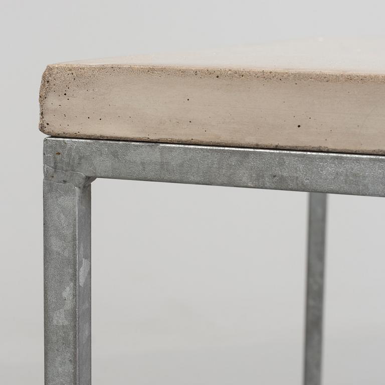 A modern sofa table with concrete top and steel legs.