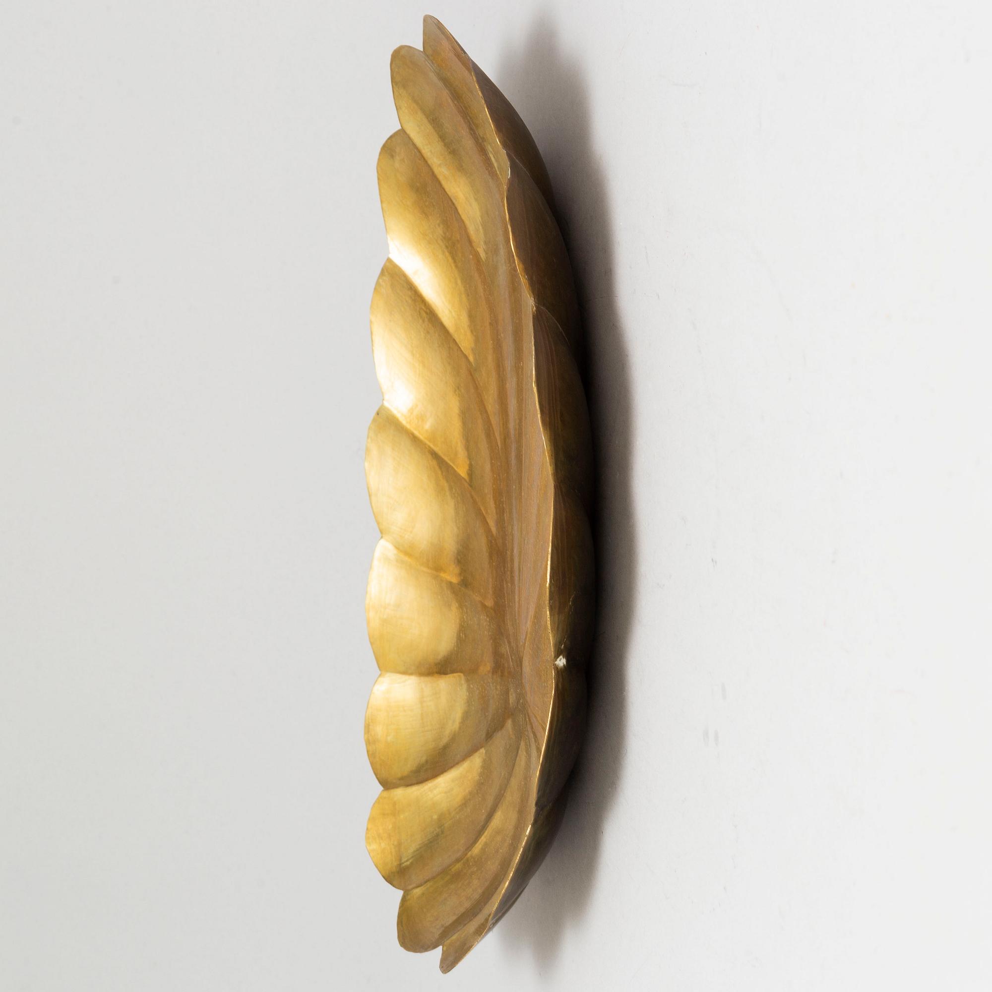 Four brass wall sconces  and one brass plate by Lars Homström, Arvika, second half of the 20th century.