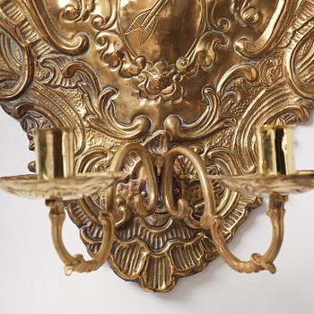 A pair of North European Rococo two-branch repoussé brass reflector plates, mid 18th century.