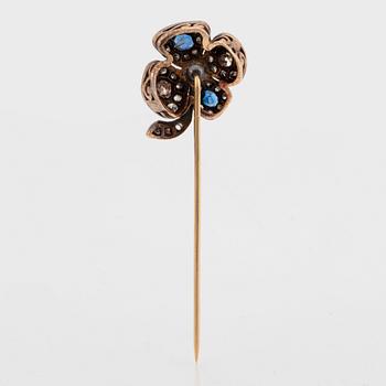 A four-leaf diamond and sapphire stick pin in platinum and 14K gold.