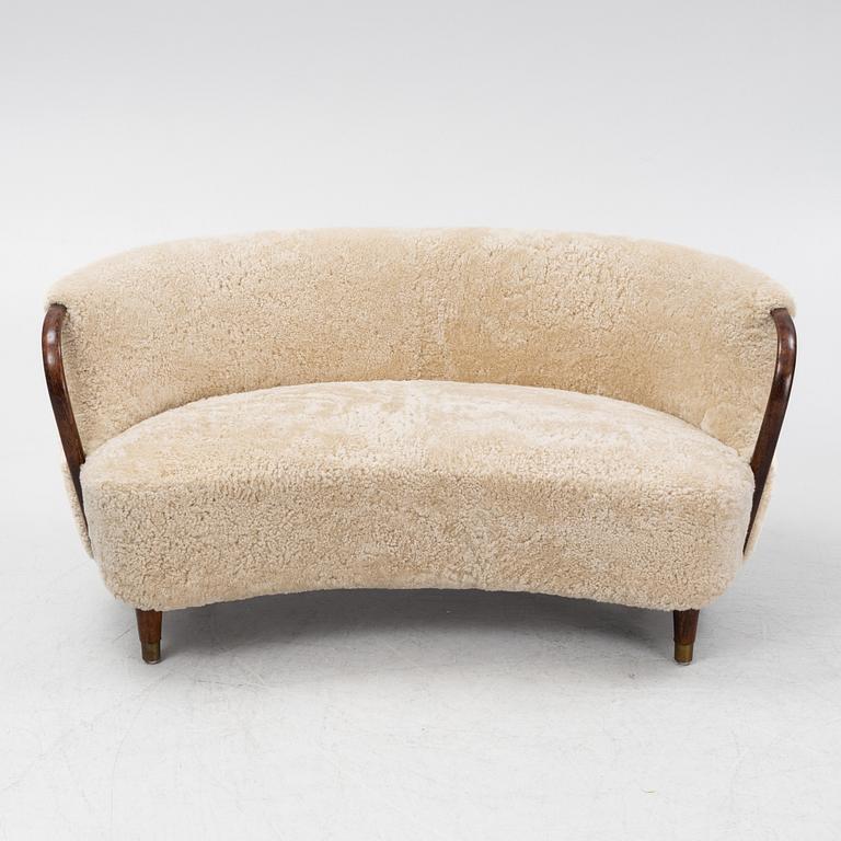 A curved sofa attributed to Viggo Boesen with new sheepskin upholstery and stained beech tree armrests.
