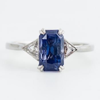 A platinum ring with an octagon scissors cut violetish blue sapphire and triangular-cut diamonds.