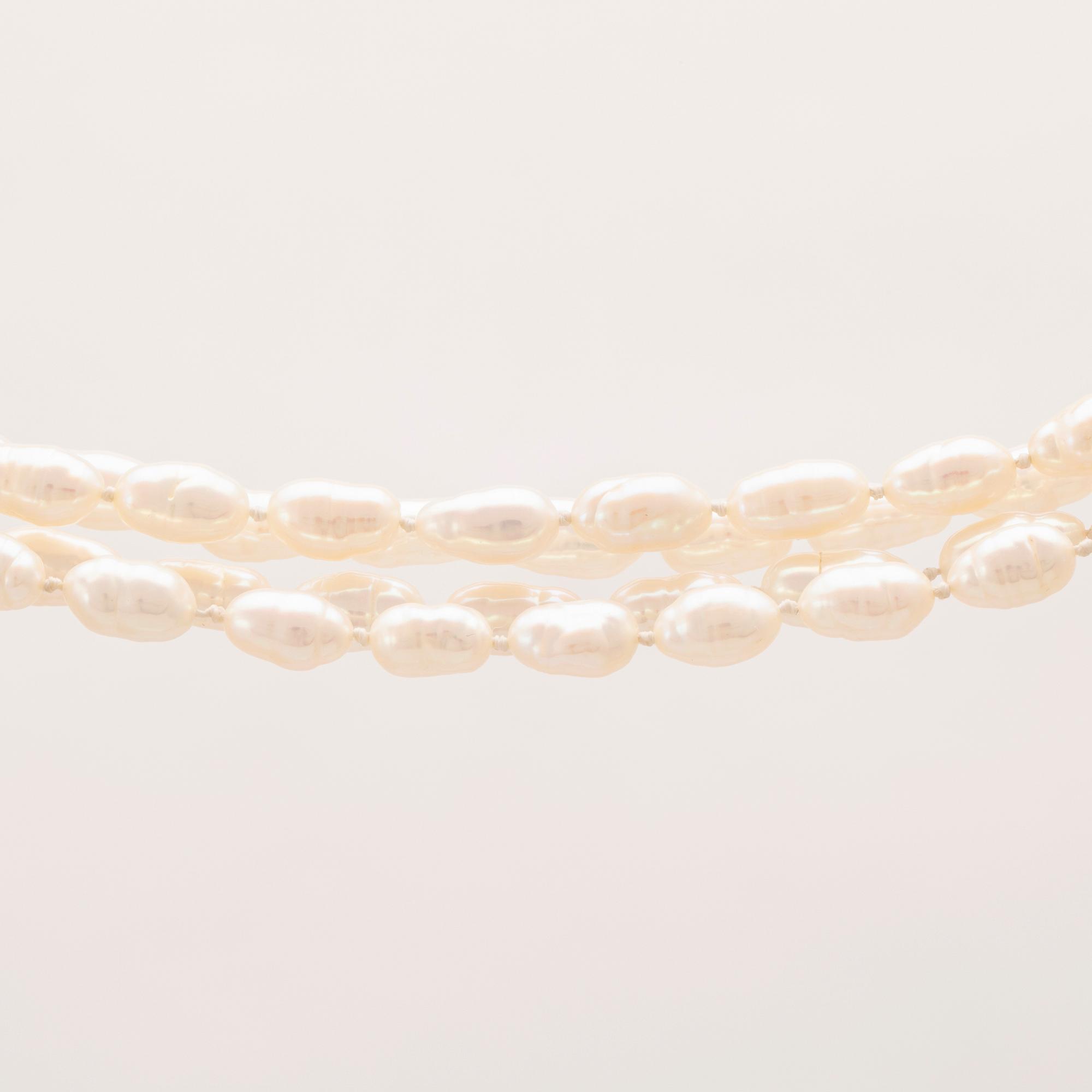 A necklace of cultured pearls set with a 14K gold lock and round brilliant cut diamonds.