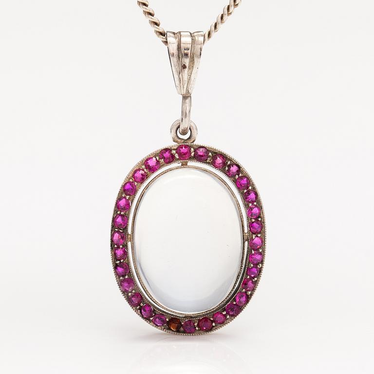 A 14K gold and silver necklace with a moon stone, rubies and a red glass stone.