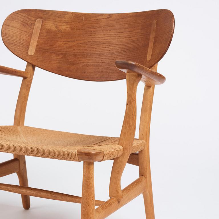 Hans J. Wegner, a pair of "CH 22" oak chairs, Carl Hansen & Son, Odense, Denmark, mid 20th century.