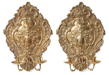 A pair of North European Rococo two-branch repoussé brass reflector plates, mid 18th century.