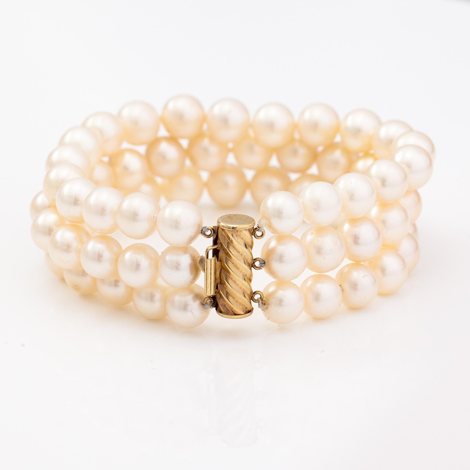 A three-strand pearl bracelet with cultured pearls and a 14K gold clasp.