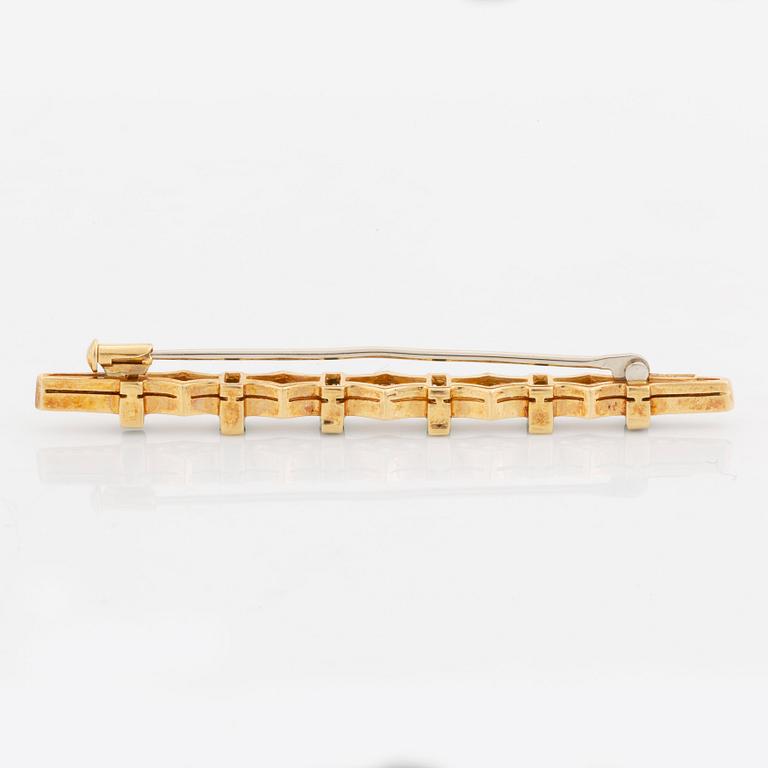 An 18K gold brooch set with step-cut emeralds and round brilliant-cut diamonds.