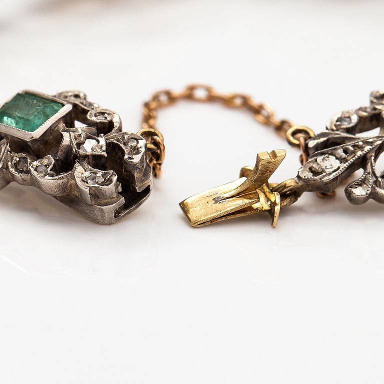 A 14K gold, silver bracelet with emeralds and diamonds.