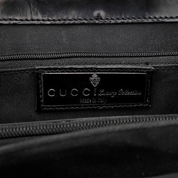 GUCCI, a black patent leather handbag.