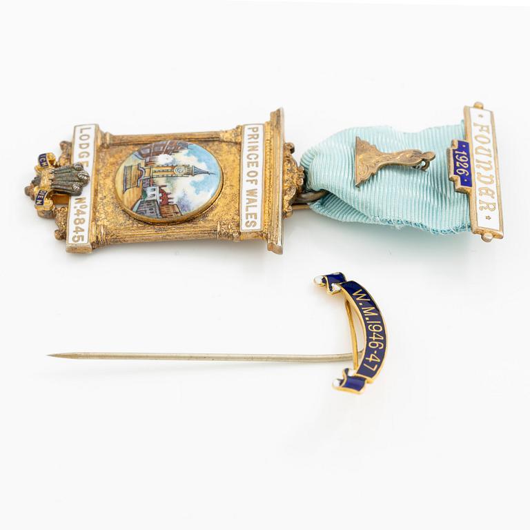 A jeton and pin, in gilded silver and 9 ct gold respectively.
