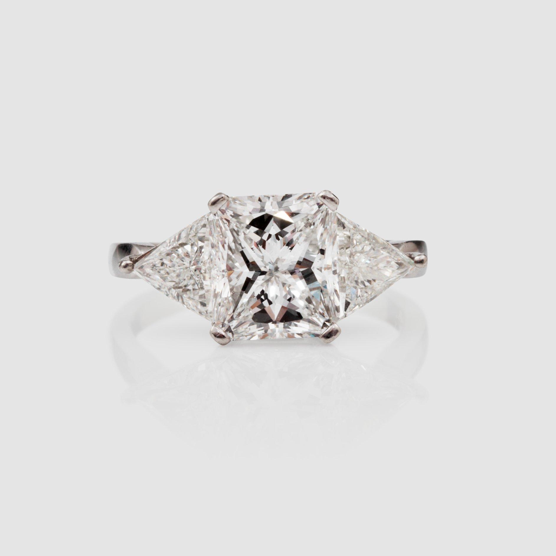 A radiant-cut diamond 3.01 cts ring. Flanked by two triangular cut diamonds, 0.50 ct each. E/VS2, certificate from HRD.