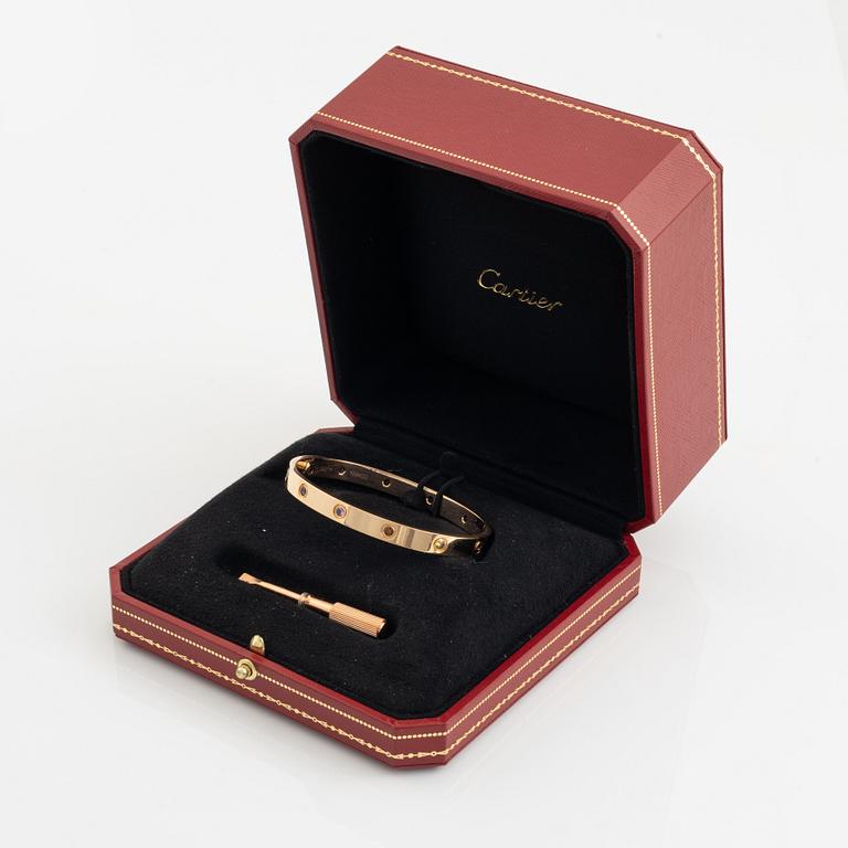 A Cartier "Love" bracelet in 18K rose gold set with colored stones.