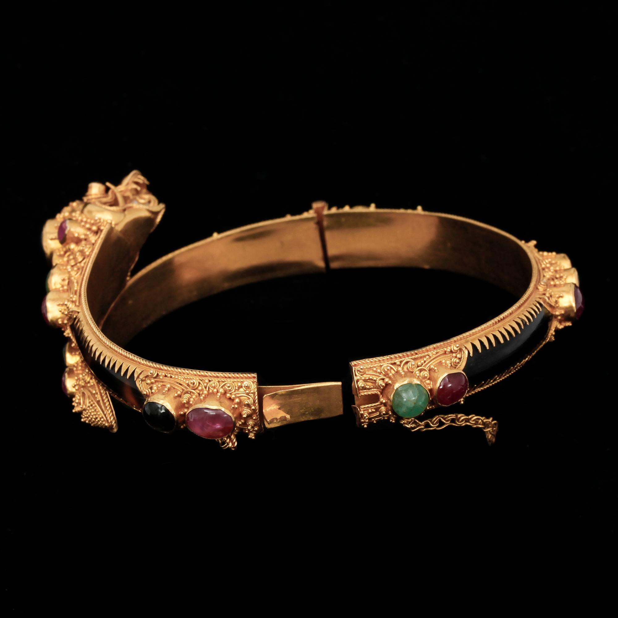 ARMBAND, 22k guld med flertal trumlade ädelstenar, bla. rubiner och smaragder. Vikt 26,9 g.