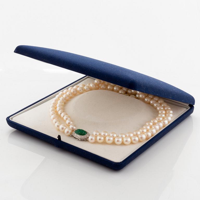 A two strand cultured pearl necklace with an 18K white gold and emerald clasp.