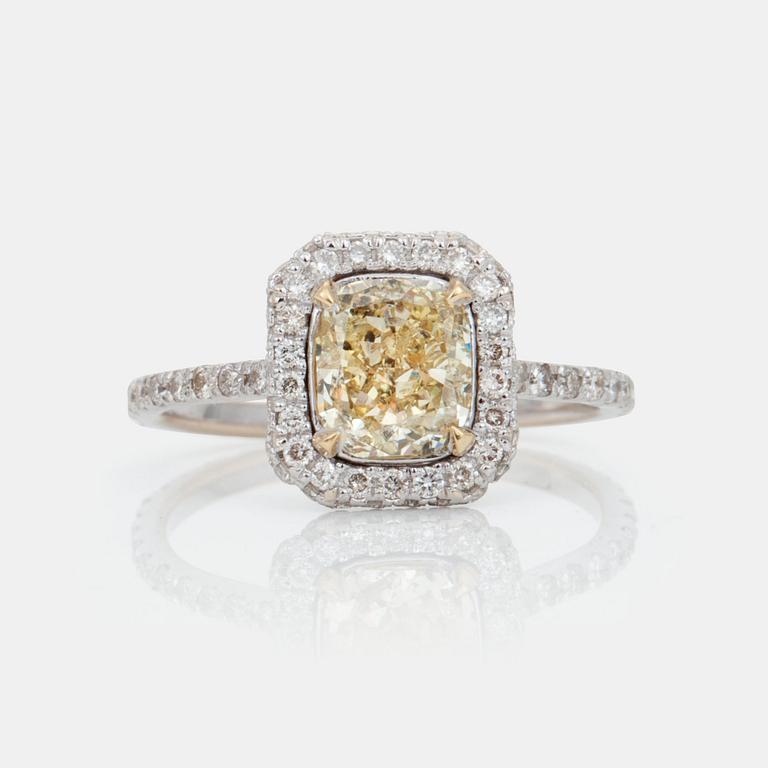 A cushion-cut fancy yellow/SI2 diamond ring. Pavé-set colourless brilliant-cut diamonds.