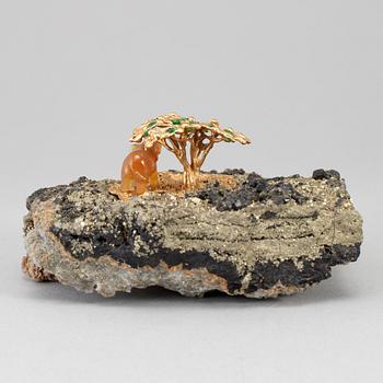 A sculpture of an agate elephant under a gilt three with inlays of tsavorites on rock formation, unmarked, 20th Century.