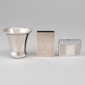 A silver vodkacup, lighter and matchholder.