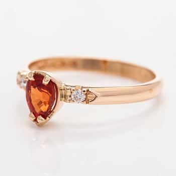 A 14K gold ring, with a pear-cut orange sapphire and diamonds.