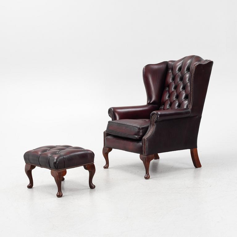 A leather upholstered wingback chair with stool. end of the 20th Century.