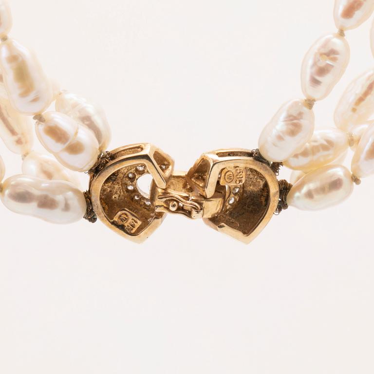 A necklace of cultured pearls set with a 14K gold lock and round brilliant cut diamonds.