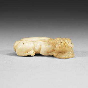 1411. A Chinese nephrite figure of a reclining buddhist lion with a coin.