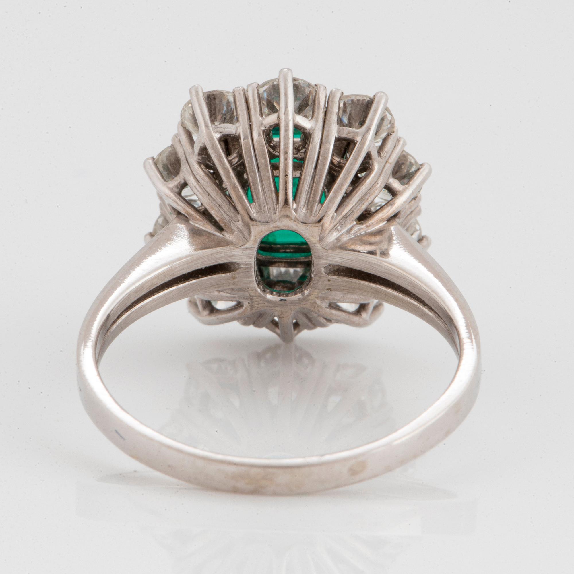 An 18K white gold ring set with a faceted emerald ca 1.15 cts and round brilliant-cut diamonds.