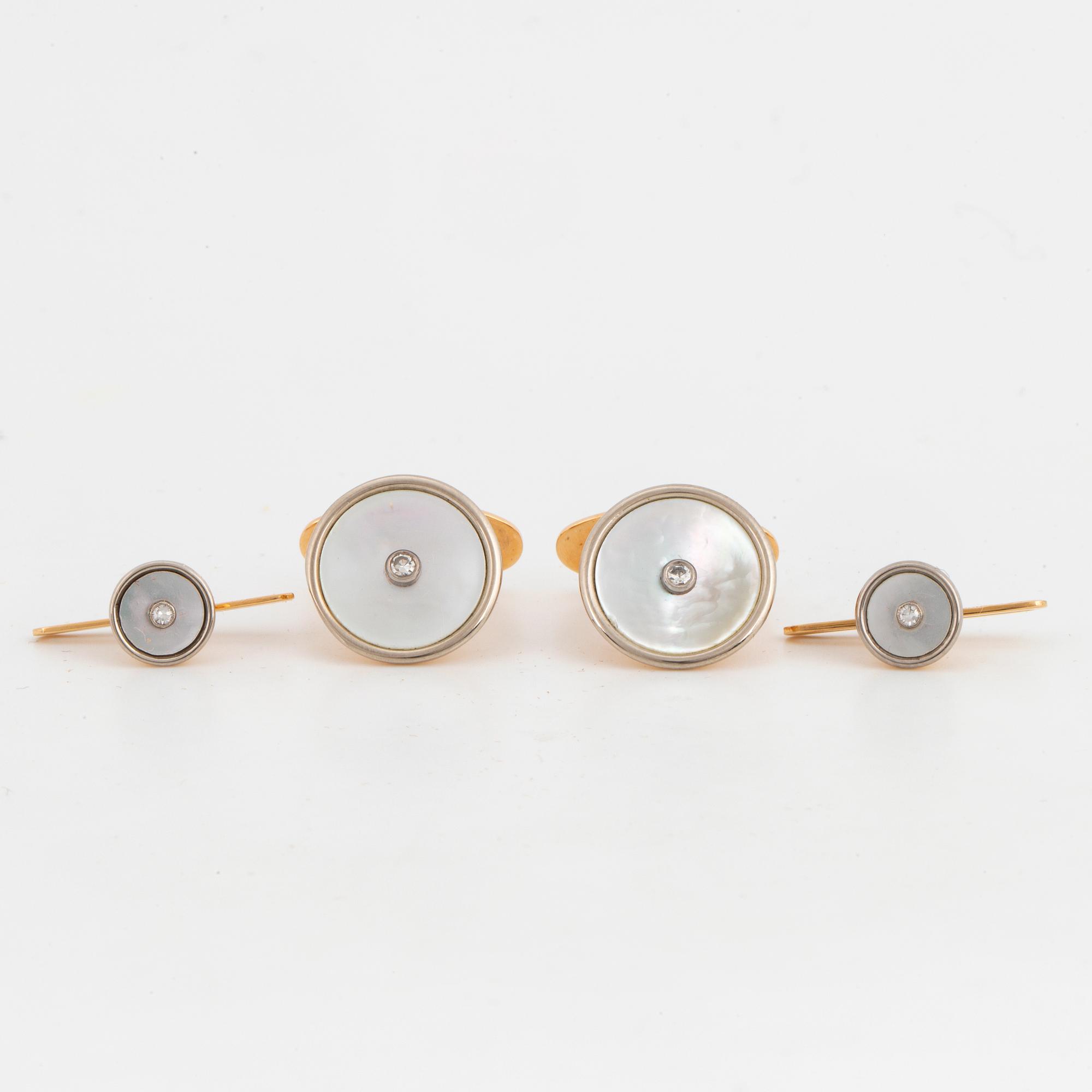 A pair of cufflinks and a pair of shirt buttons.