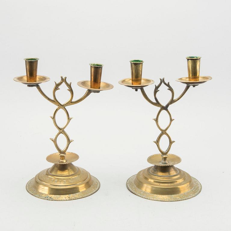 A pair of brass candelabras dated 1810 and 1812.