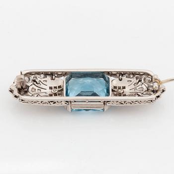 An 18K white gold brooch set with a faceted aquamarine and round brilliant- and rose-cut diamonds.