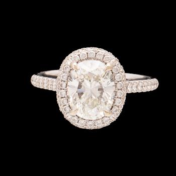 An 18K white gold ring by James Allen, set with an oval brilliant cut diamond in a halo of round brilliant cut diamonds.