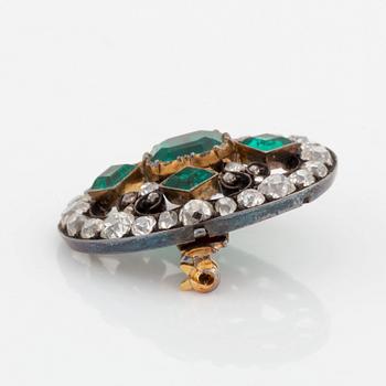 A gold and silver brooch set with faceted emeralds and old- and rose-cut diamonds.