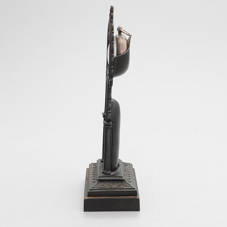 A neo-gothic cast iron pocket watch stand with a pocket watch. 19th century.