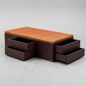 A contemporary bench with drawers and leather upholstery.