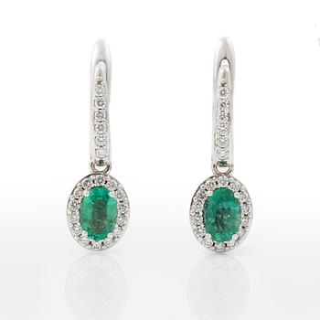 A pair of earrings with faceted emeralds and round brilliant-cut diamonds.