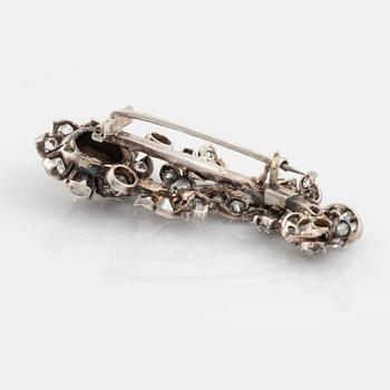 A flower silver brooch set with old-cut diamonds.