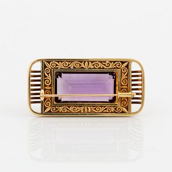 A 14K gold brooch set with a faceted amethyst and eight-cut diamonds.