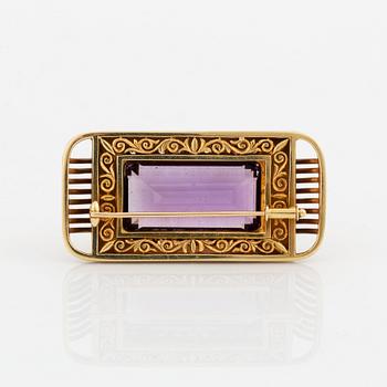 A 14K gold brooch set with a faceted amethyst and eight-cut diamonds.