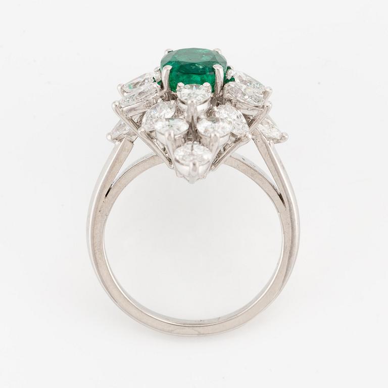 An platinum ring set with a faceted emerald and brilliant-cut pearshaped diamonds.