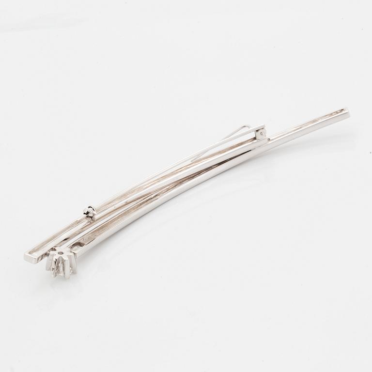 A 14K gold brooch set with a round brilliant-cut diamond.