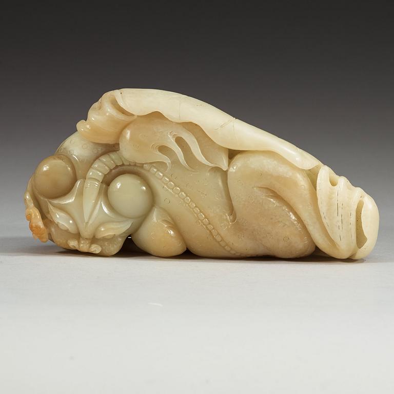 A large Chinese nephrite sculpture of a mythological beast on a  lotus leaf with coins and a bat.